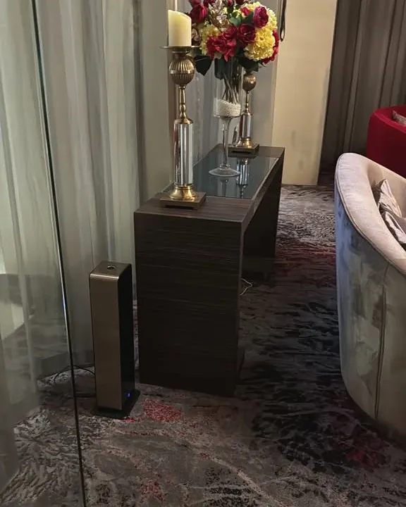 Bronze tower scent diffuser beside a console table in a hotel suite