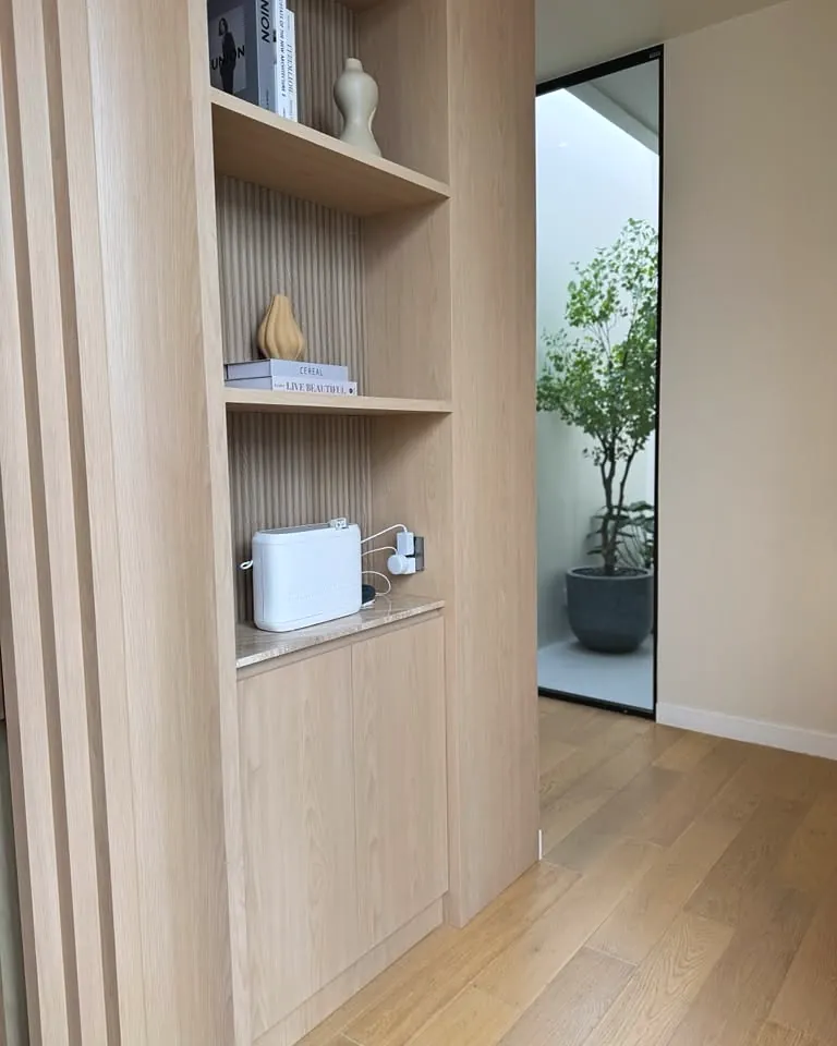 Compact white scent diffuser on a built-in oak shelf in a residential hallway